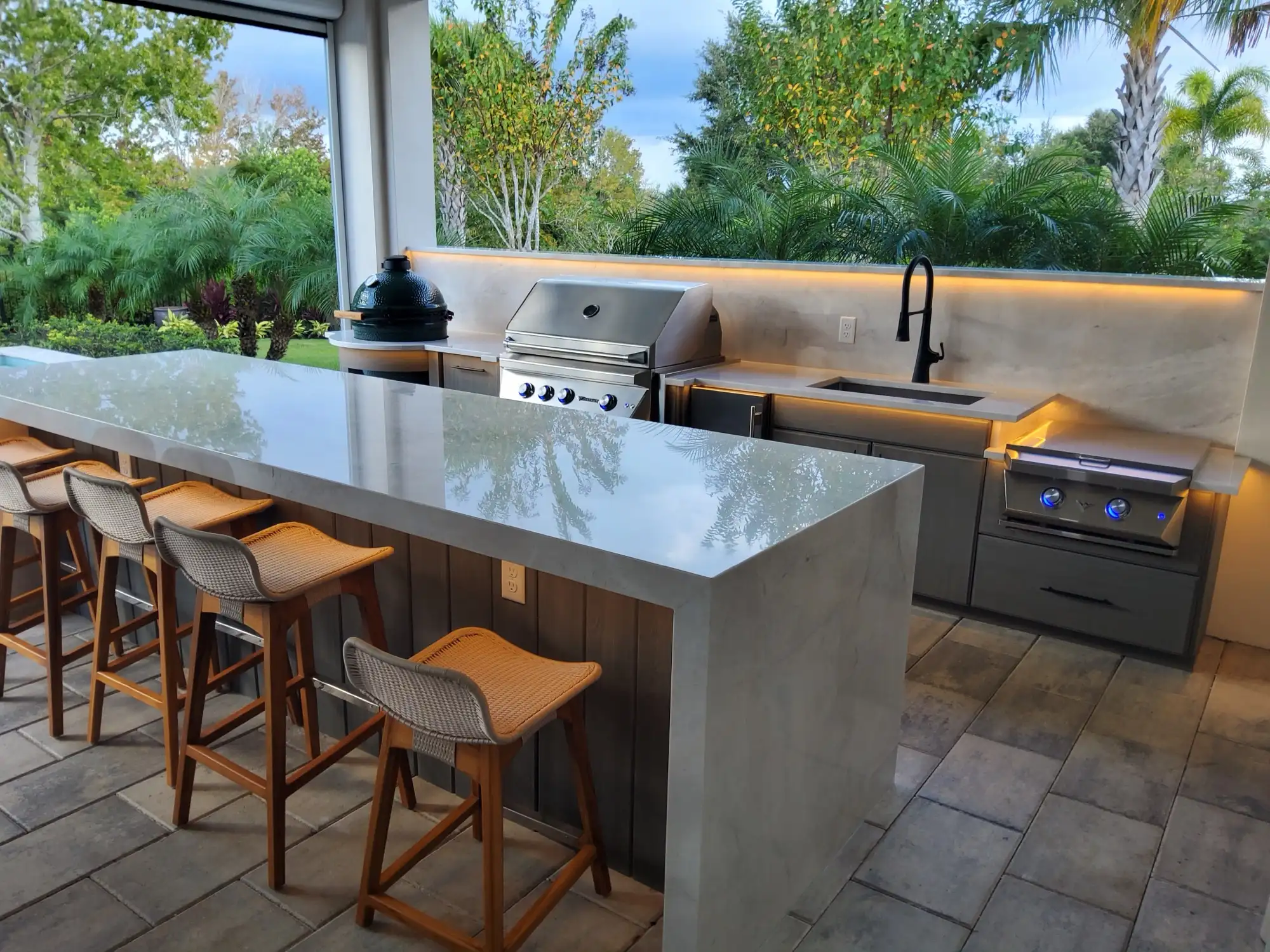 Custom outdoor kitchen built by Patio Style in Orlando, with a marble waterfall island and built-in grill