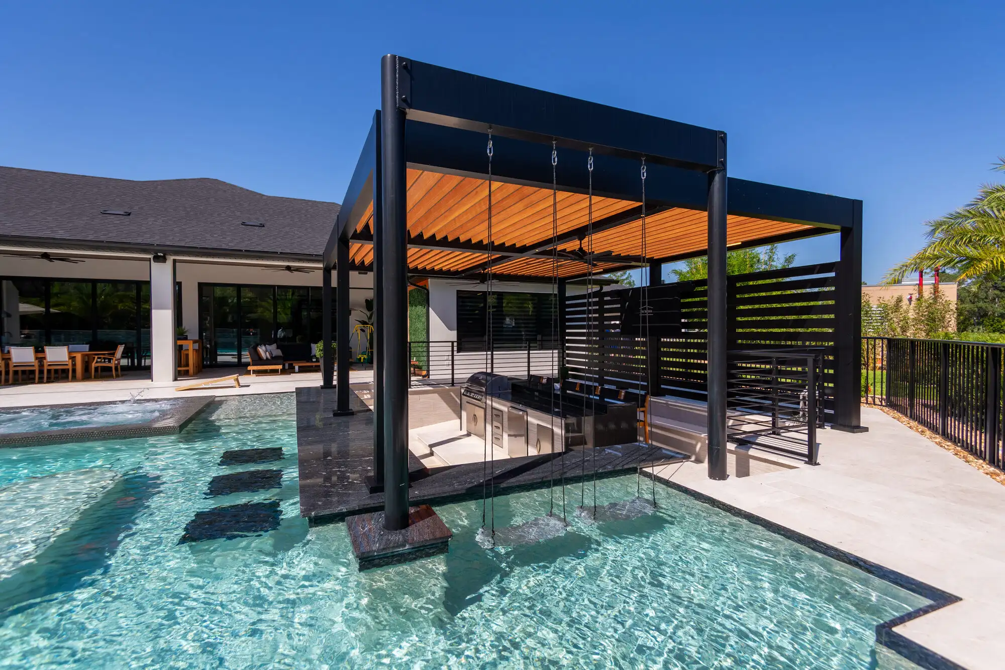 Black aluminum louvered pergola over a poolside patio in New Smyrna Beach, FL by Patio Style